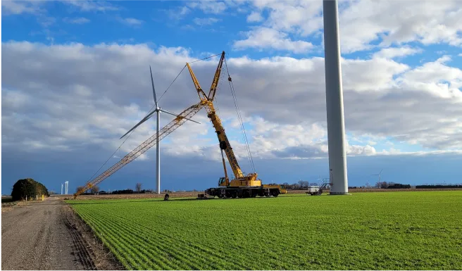crane lifting a large piece of equipment onto a field