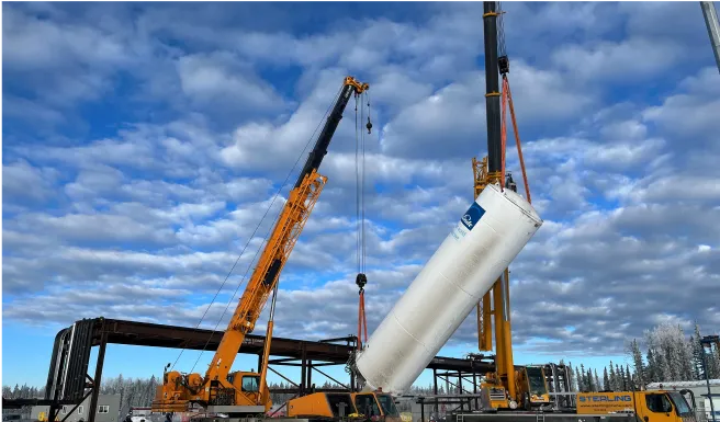 crane lifting a large piece of white material onto a truck
