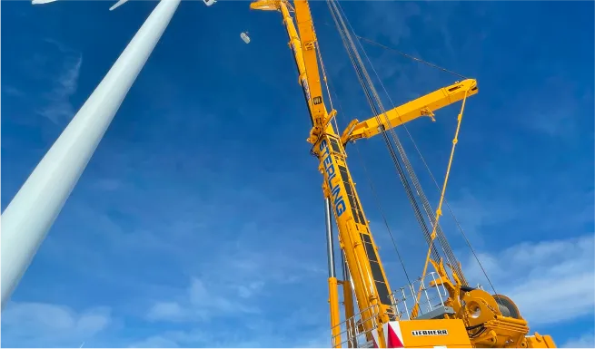 crane lifting a wind turbine into position on a sunny day