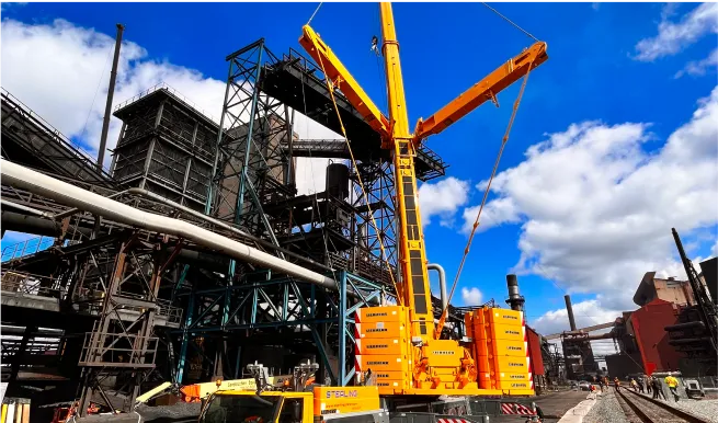 crane lifting a large piece of equipment onto a truck