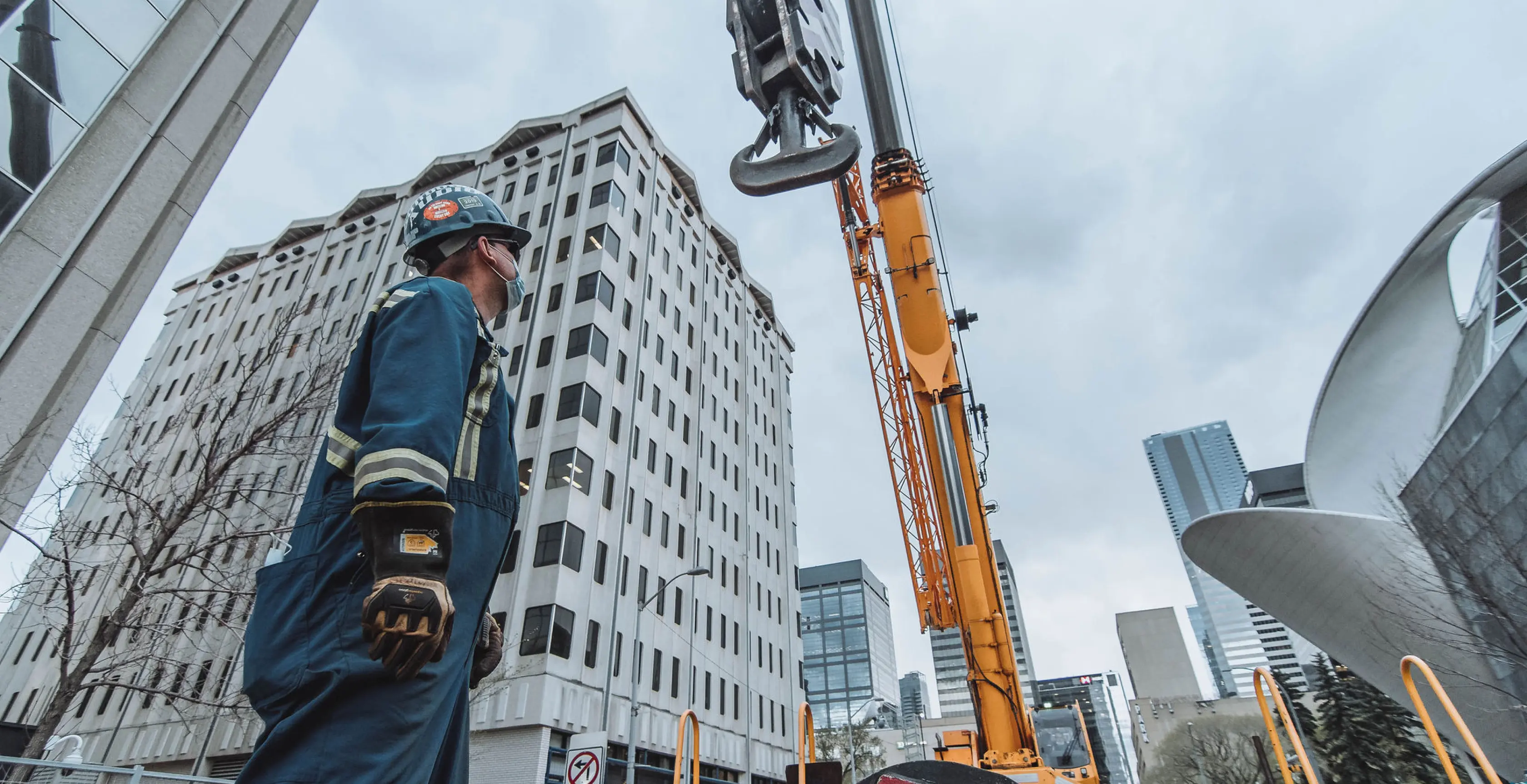 A man standing next to a crane at a construction site.