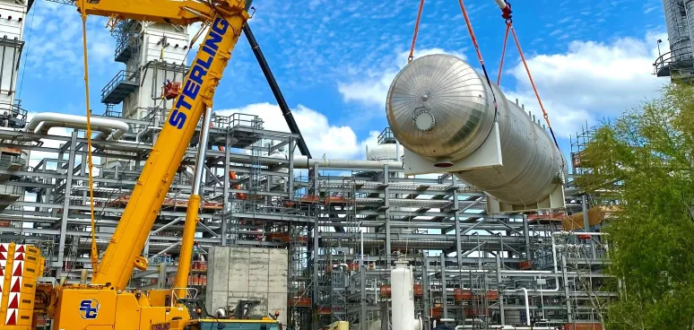 crane lifting a large metal object from a large building