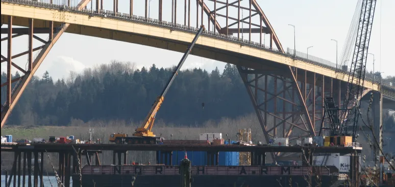 there is a crane that is standing on a bridge over water