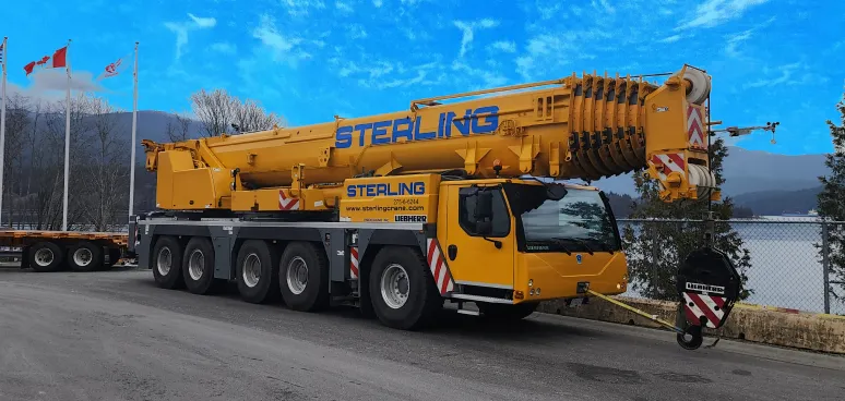 crane on a trailer on a road near a lake