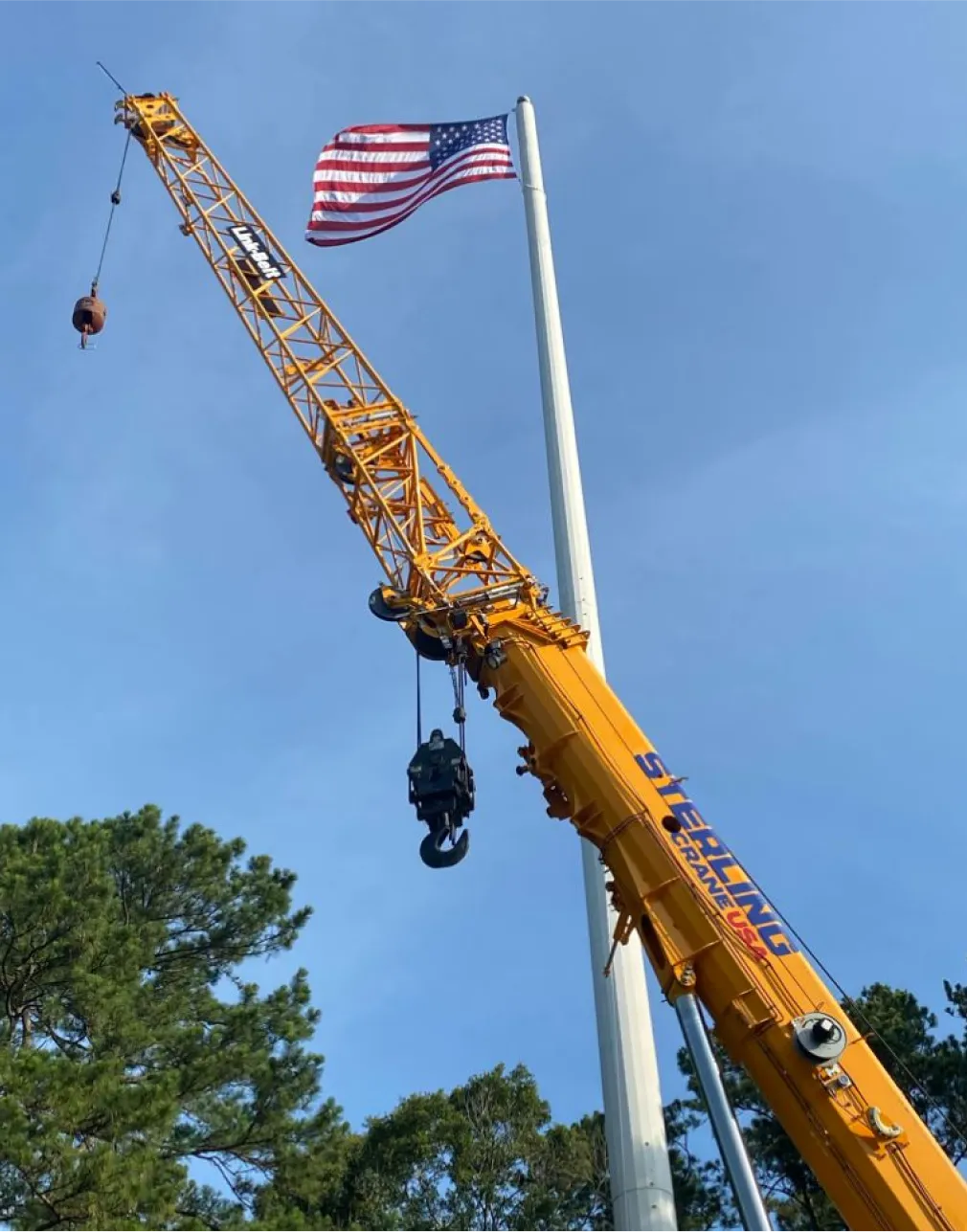 there is a crane that is lifting a flag on a pole