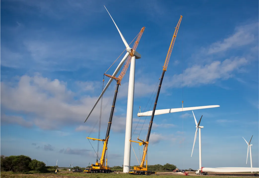 windmills being constructed in a field with a crane