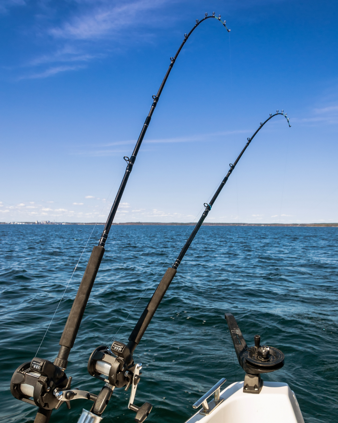 Two trolling rods bent over the ocean from a boat