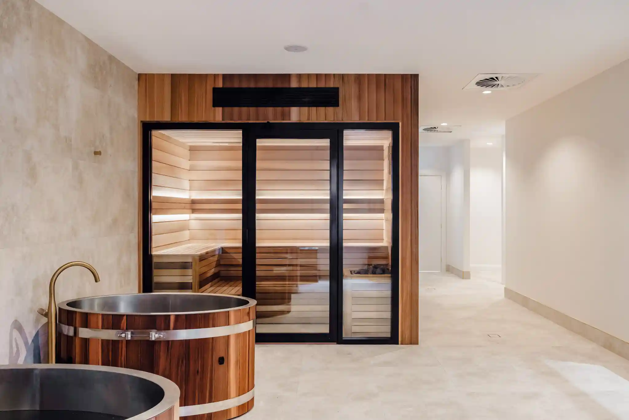 Wellness area with wooden soaking tubs and an illuminated sauna.