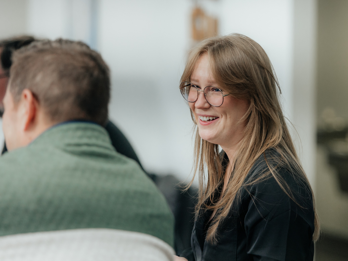 A Dispatch team member smiling during a conversation with colleagues in the office.