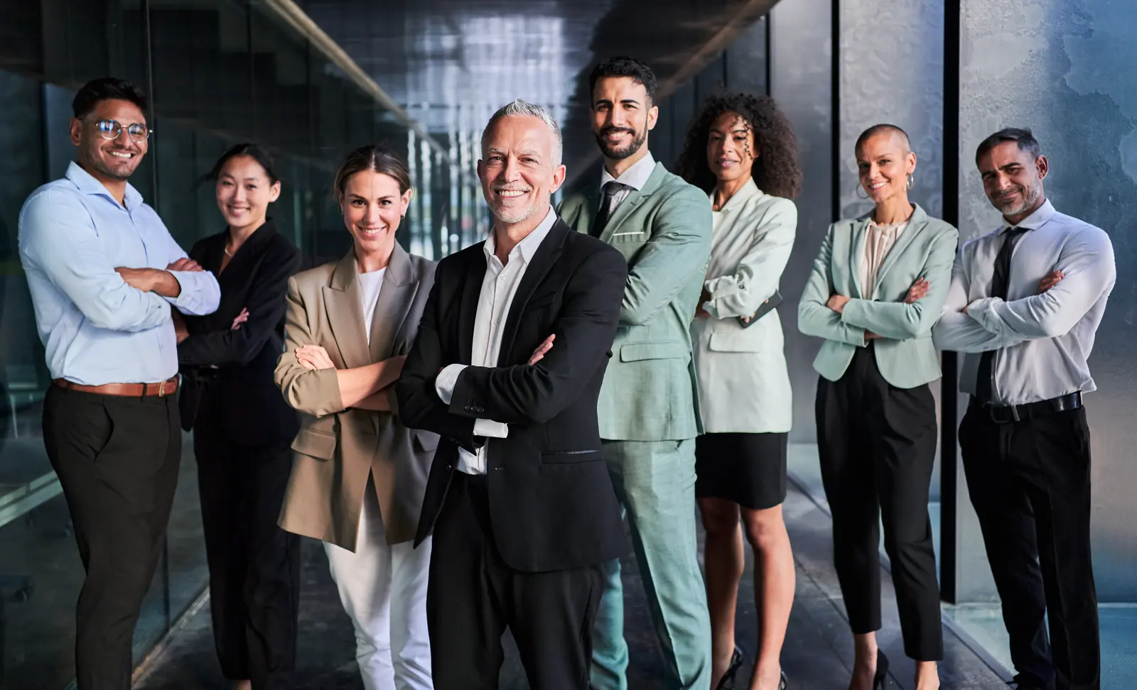 A professional portfolio team standing together in a modern hallway, representing standardized operations and increased operational visibility across a utility services portfolio.