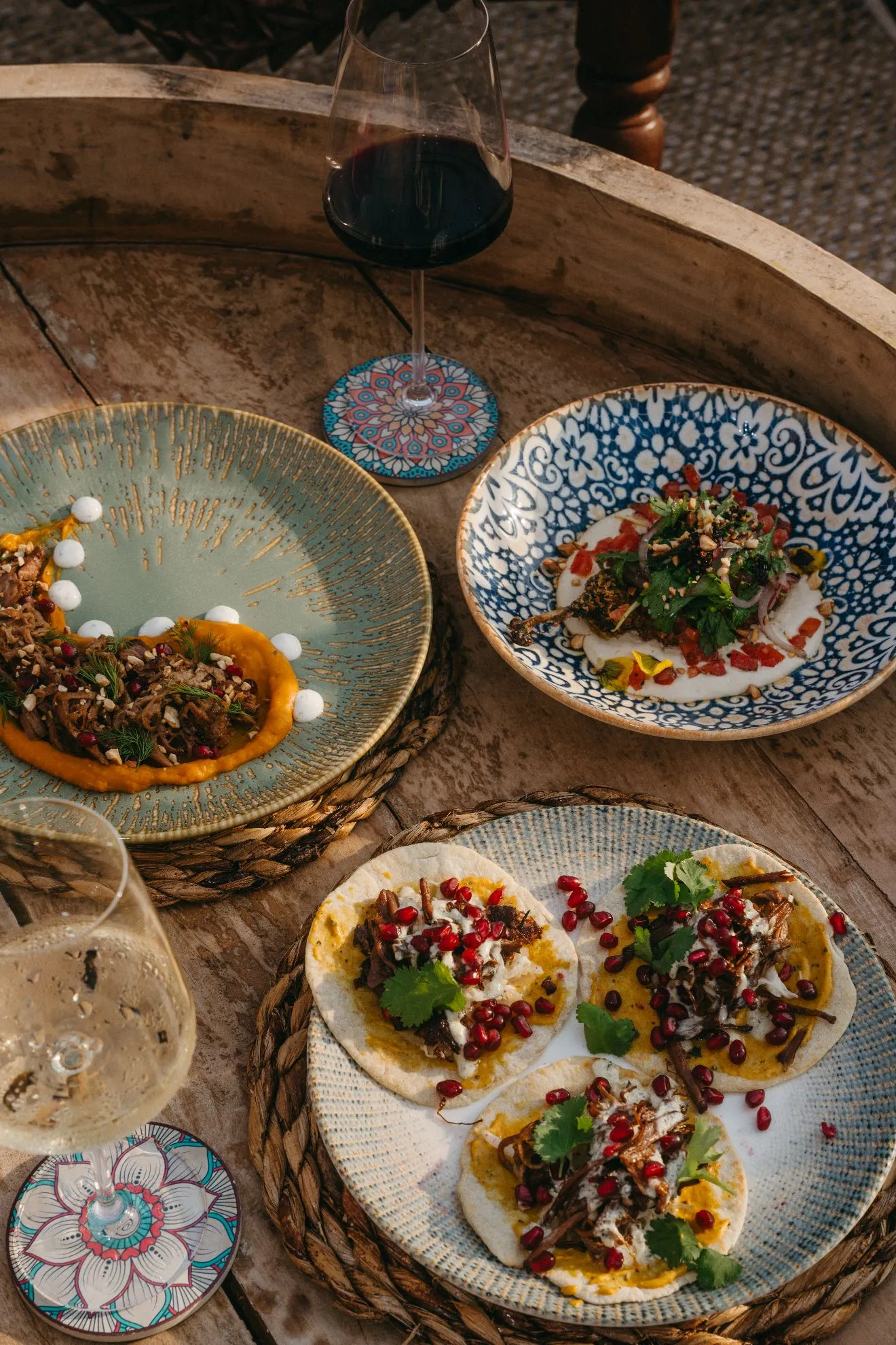 Shared plates and wine on a wooden table aboard Musafir