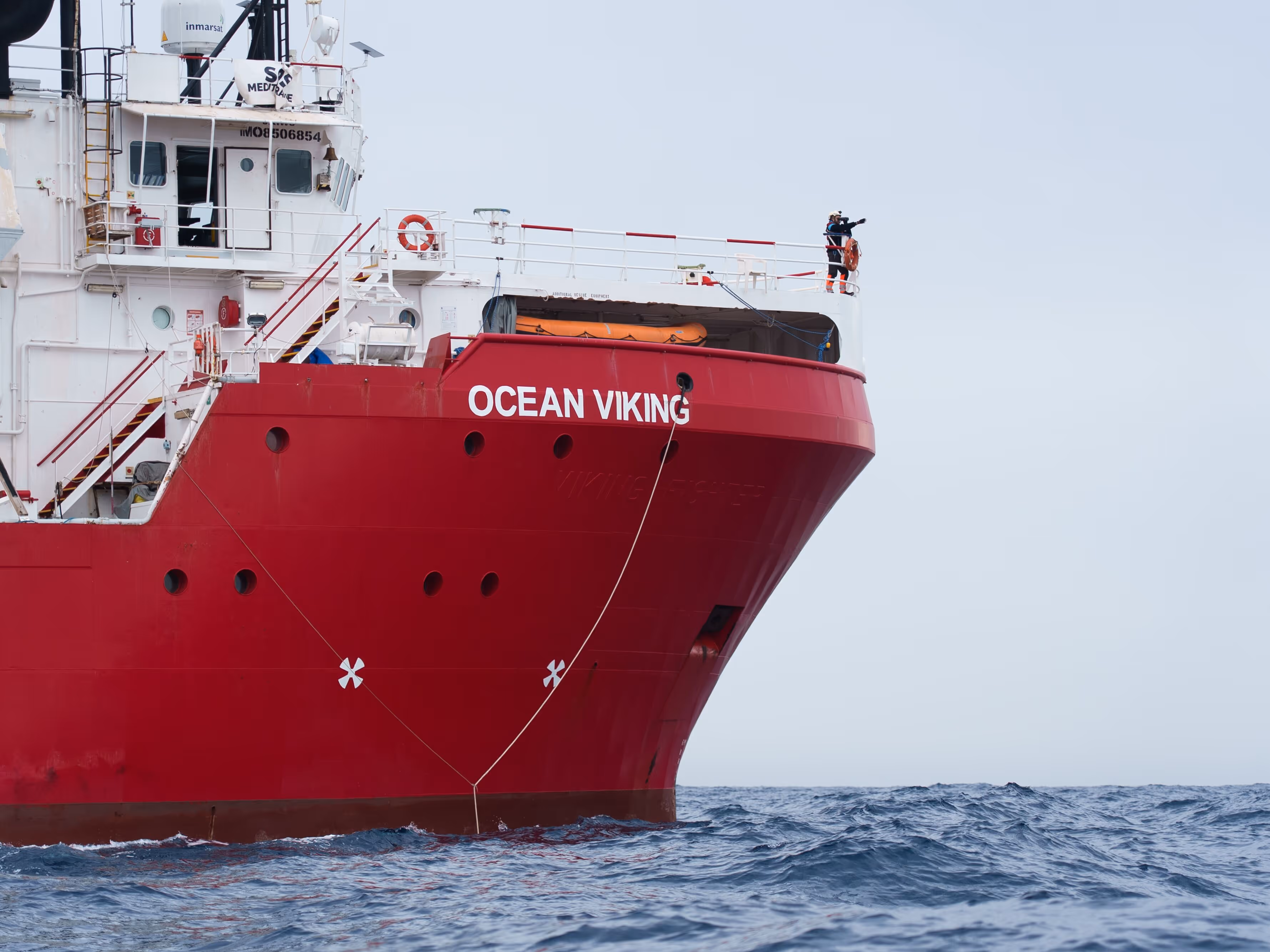 A sea rescue ship named ocean viking with a person on the ship searching for human in distress at sea.