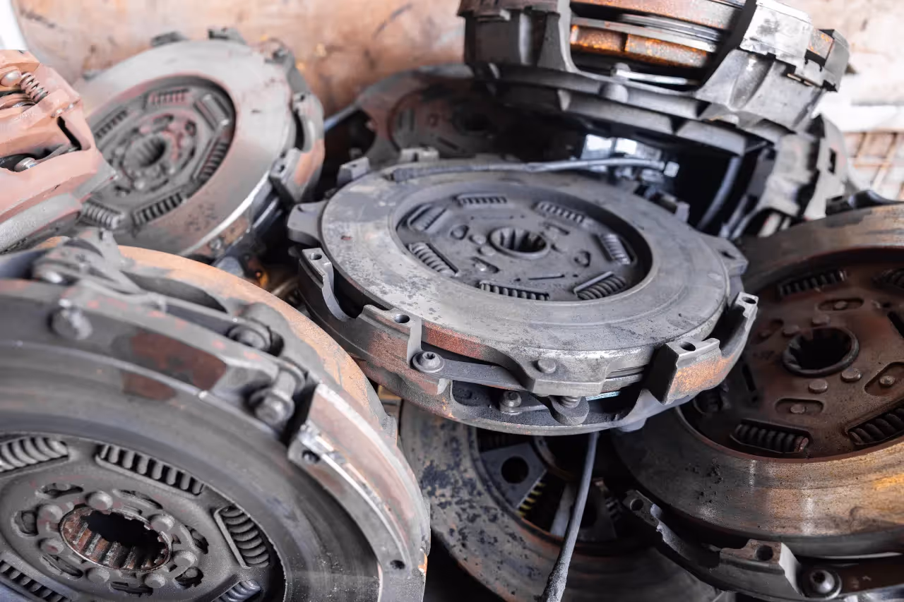 Stack of worn heavy-duty clutches with visible rust and grime awaiting refurbishment.