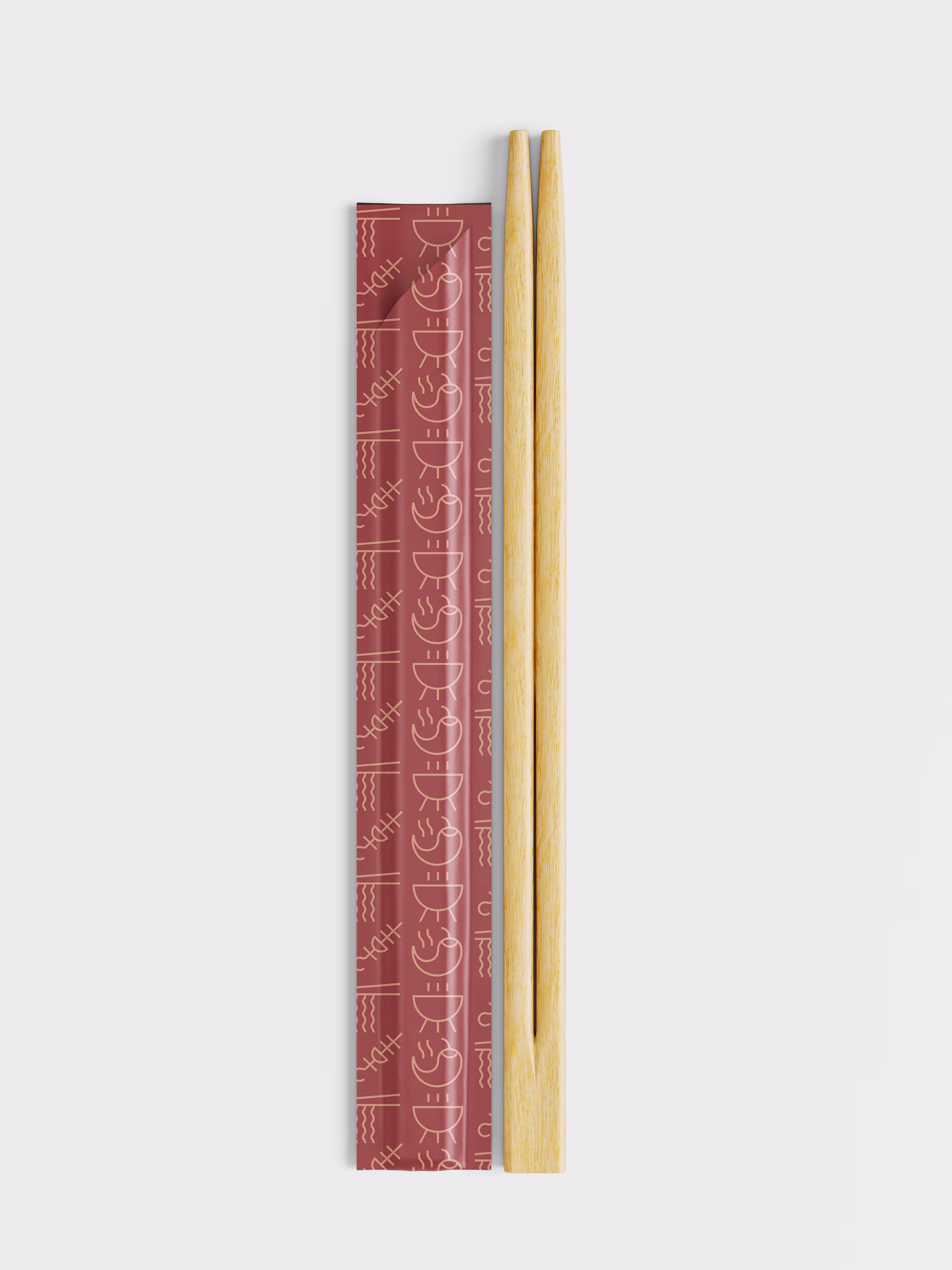 A pair of wooden chopsticks lying next to their closed, maroon-colored paper wrapper which is decorated with a light brown abstract pattern