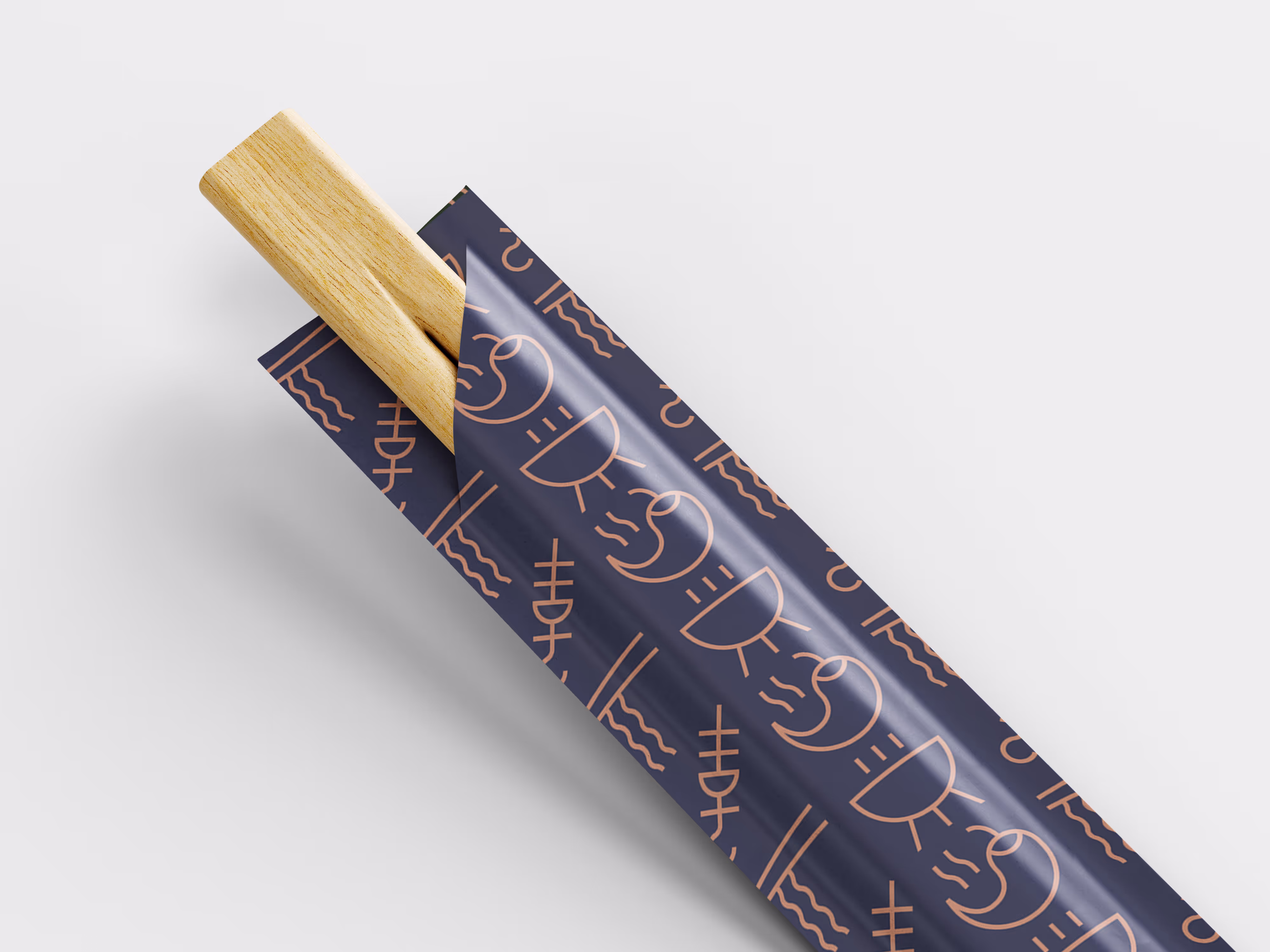 A close-up of a pair of wooden chopsticks partially removed from a dark blue paper wrapper decorated with a light brown abstract pattern