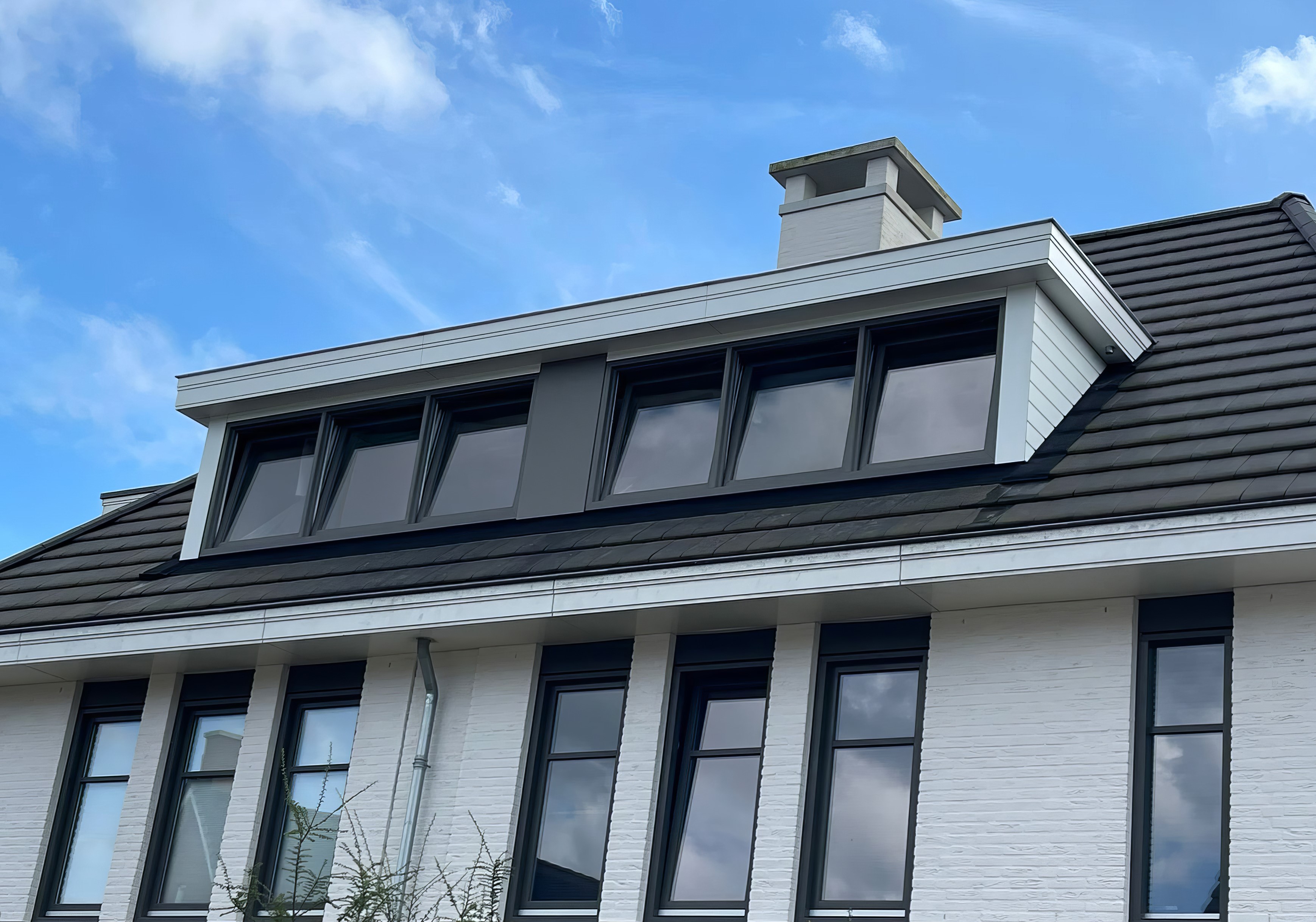 Lukarna w kolorze białym na budynku z czarnym dachem i białą elewacją