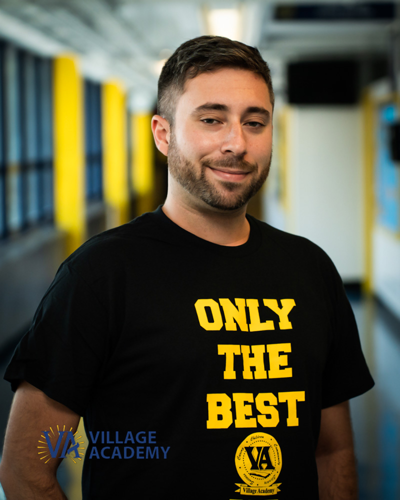 Mr Kaplan smiling in a Village Academy school hallway