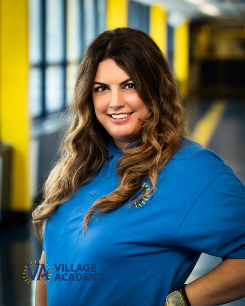 Village Academy staff member Ms Gimenez smiling in school hallway