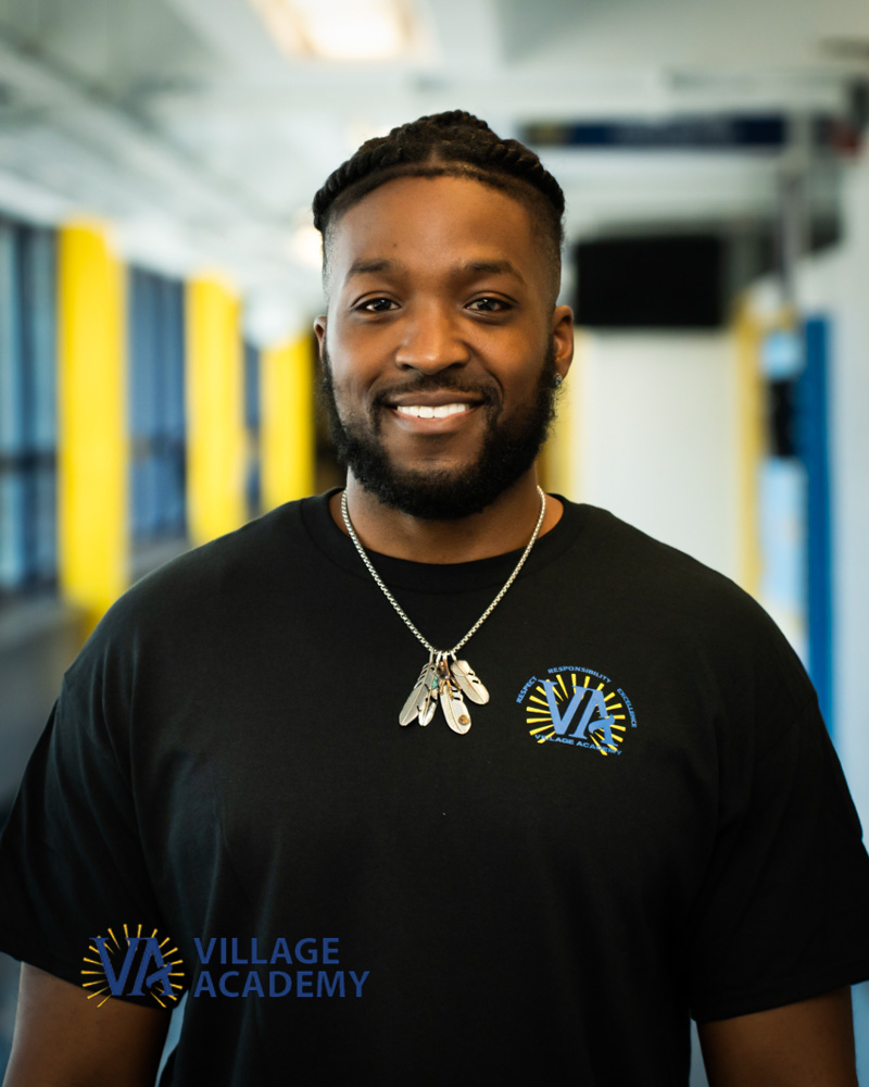 Mr. Hollingsworth smiling in Village Academy school hallway