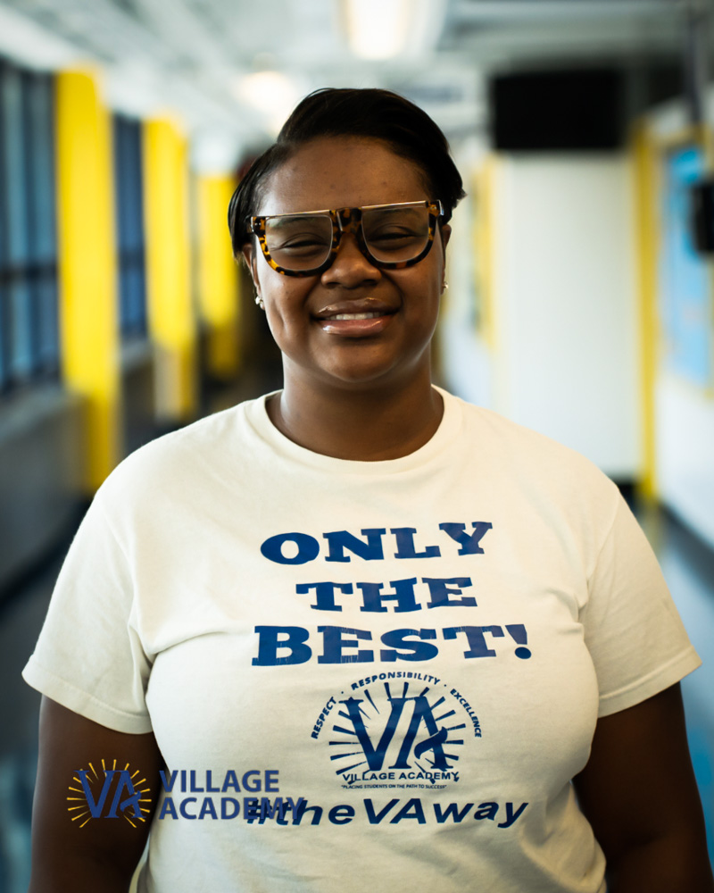 Ms. M. Sidberry smiling in a Village Academy school hallway