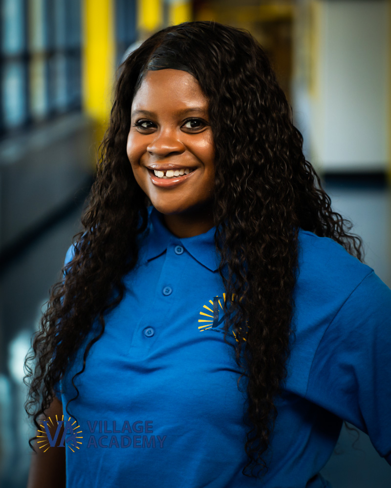Ms. Ennis smiling in Village Academy blue polo uniform