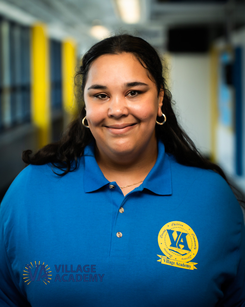 Ms. Lee smiling in Village Academy uniform in school hallway