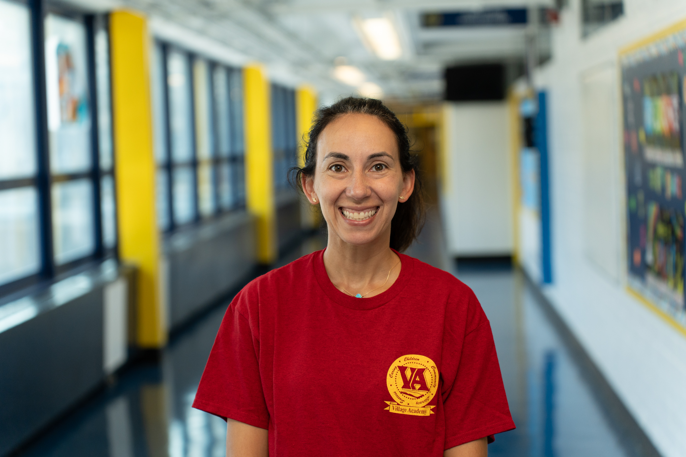 Ms. L. Weissman smiling in a Village Academy school hallway