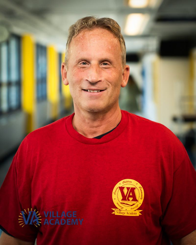 Village Academy staff member Mr Apter smiling in school hallway