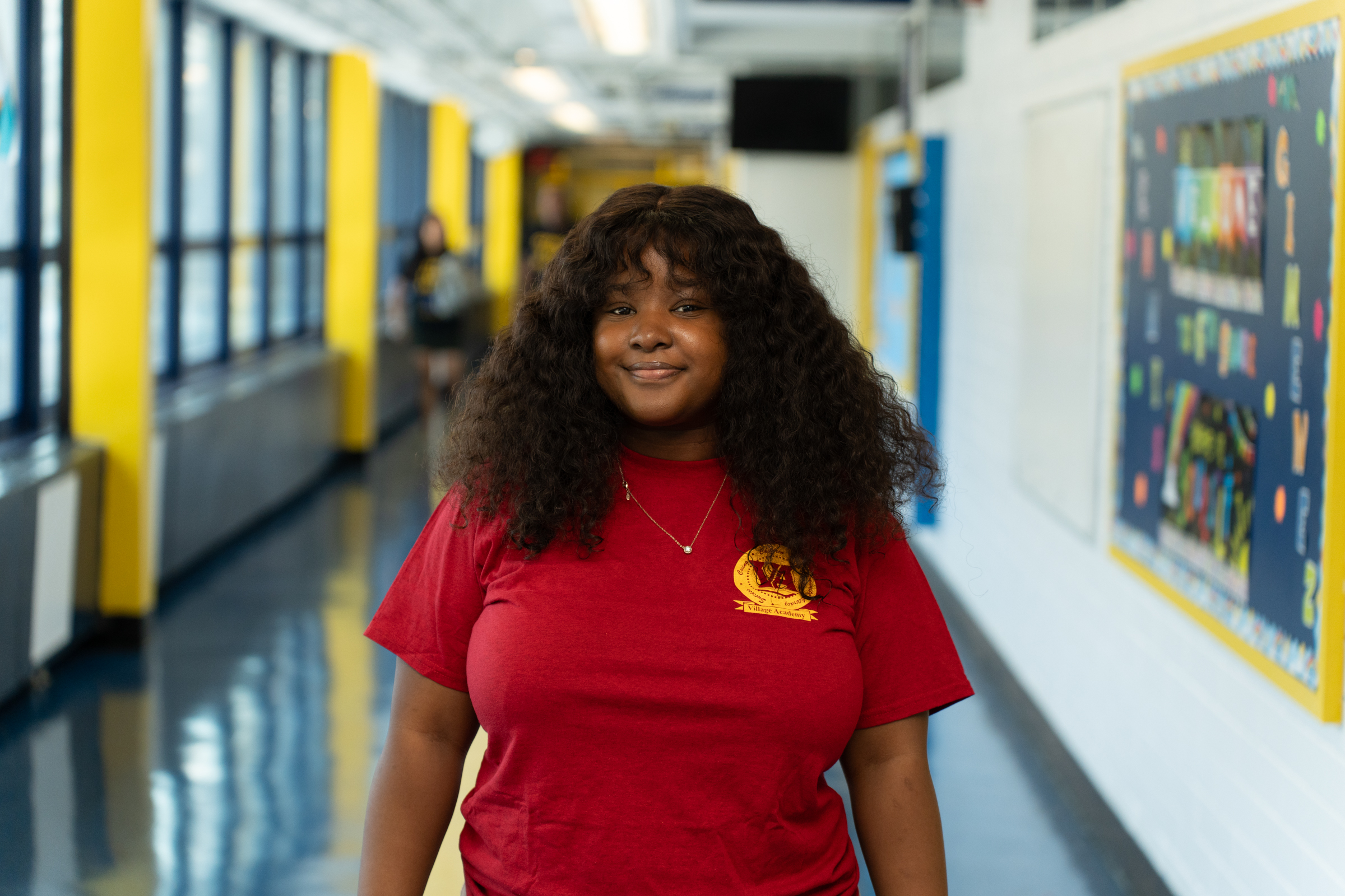 Chelsea Etienne smiling in a school hallway wearing a red VA shirt