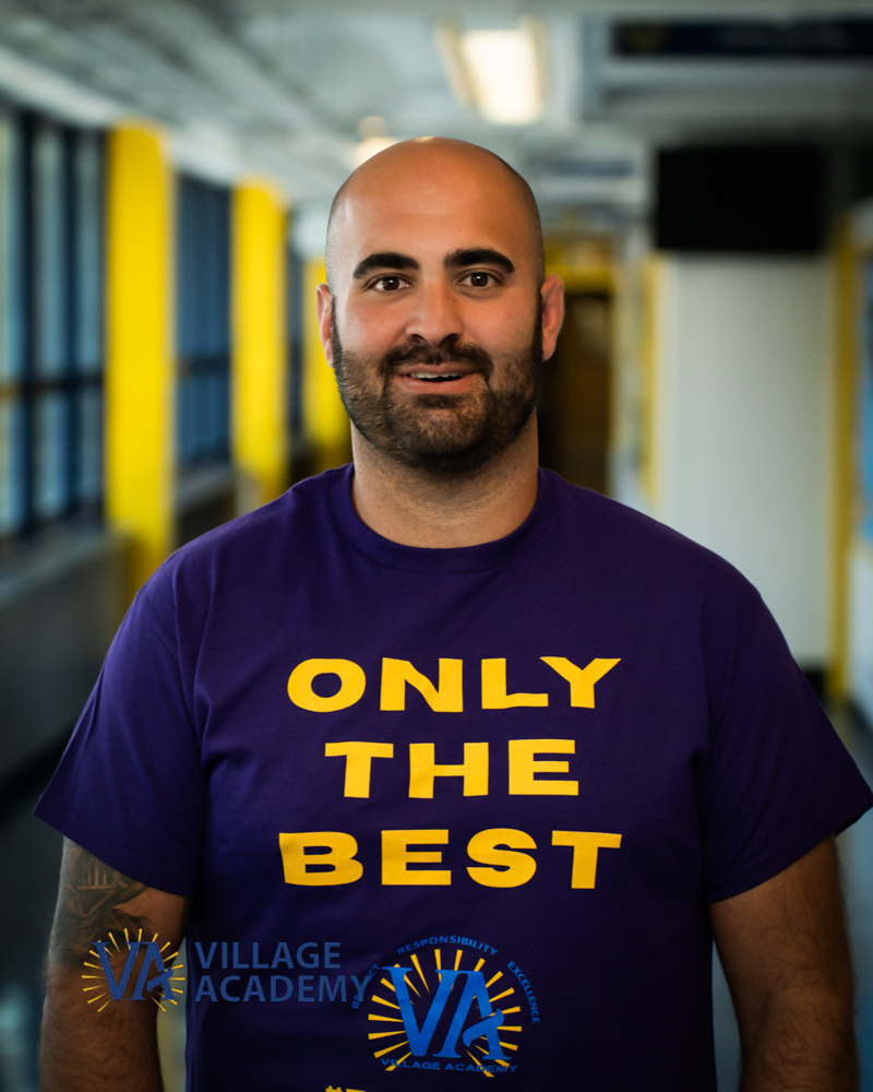 Village Academy staff member Mr Schuerlein smiling in school hallway