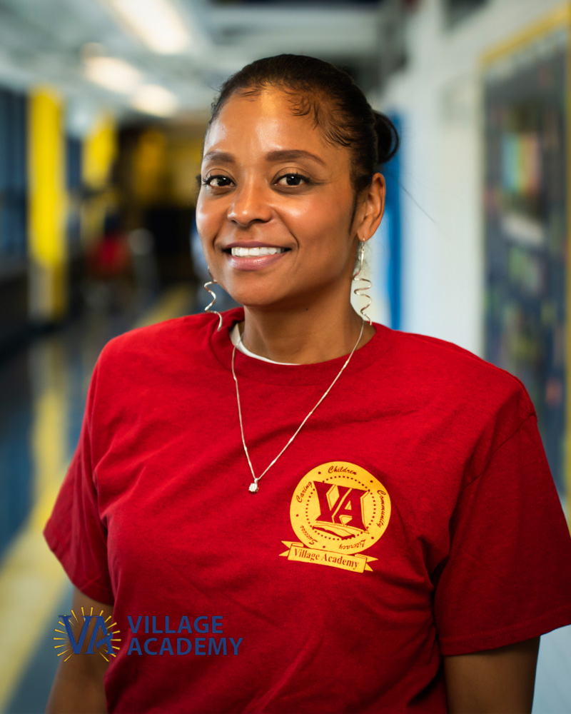 Ms. Simmons smiling in a Village Academy staff shirt