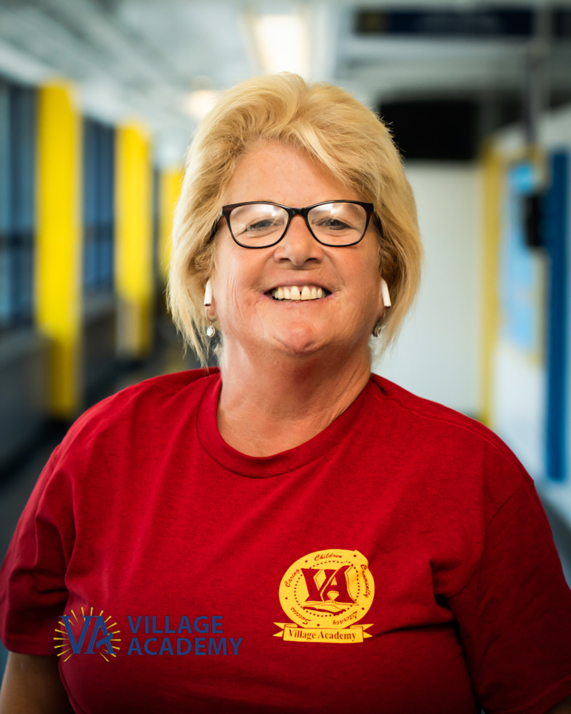 Village Academy staff member Ms T Ganun smiling in school hallway