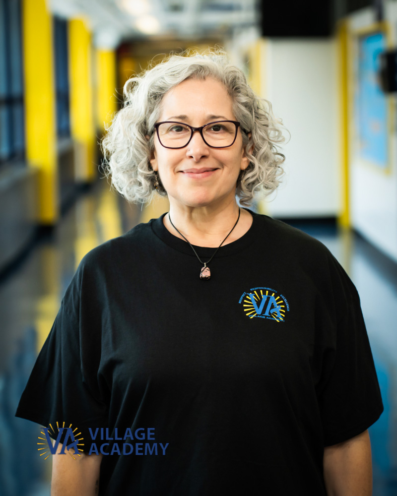 Village Academy staff member Ms. Keynan smiling in school hallway