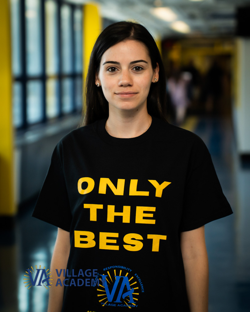 Ms. Rodriguez smiling in a Village Academy school hallway