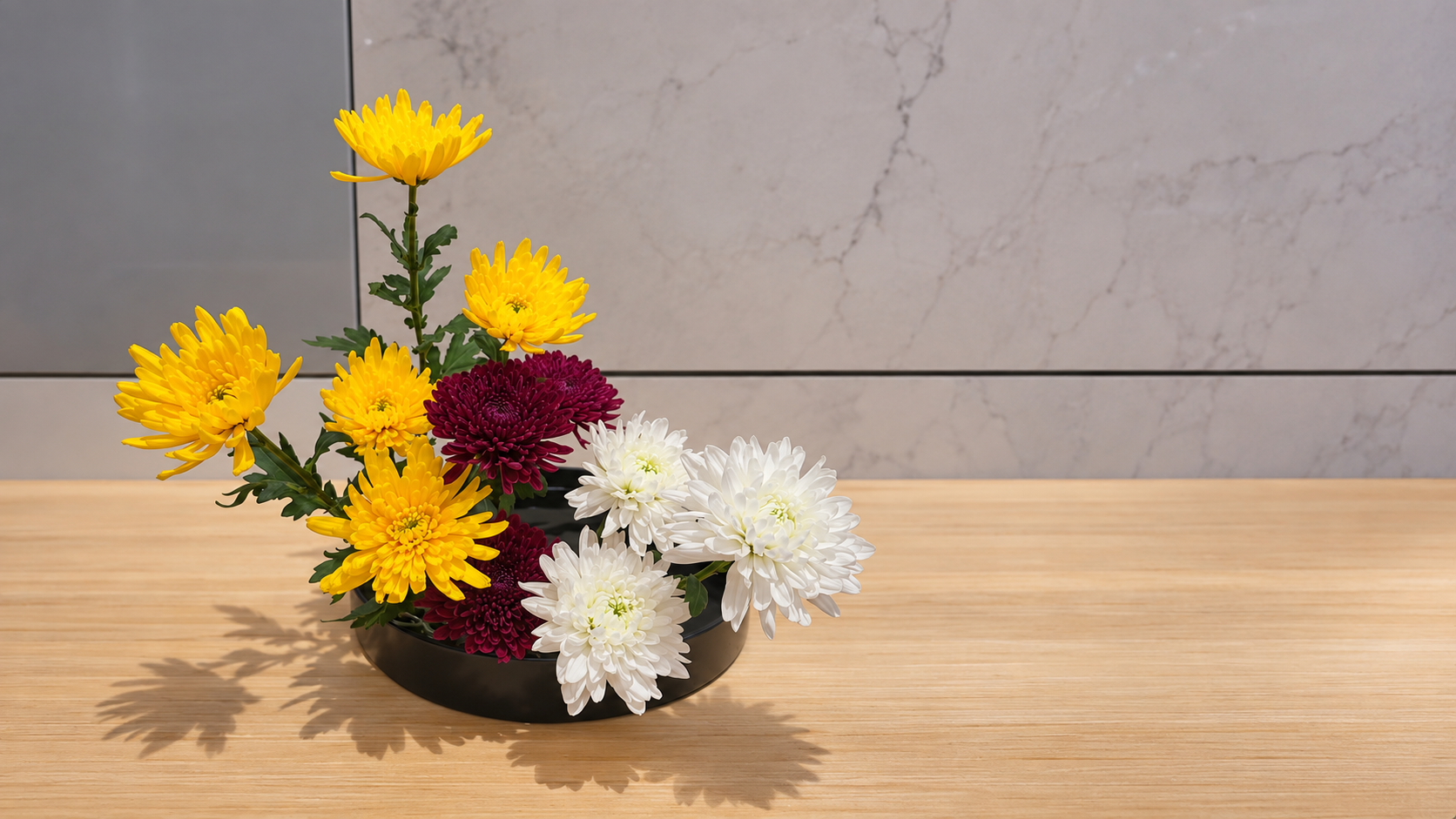 Three-color chrysanthemum Moribana arrangement by Kiyoichi Kamo-sensei, featuring yellow, deep red, and white chrysanthemums in a low black container.