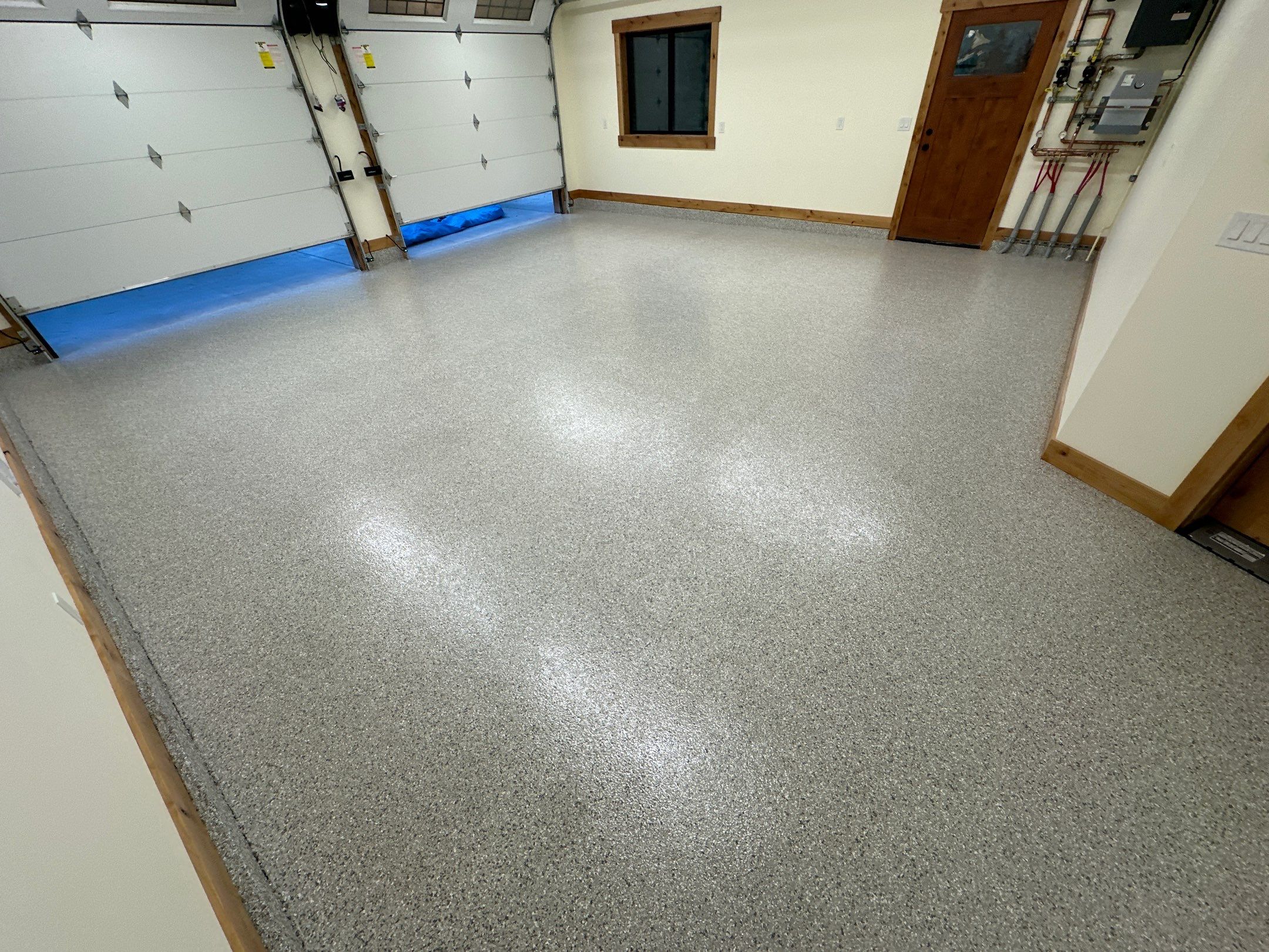 Mount Everest flake polyurea garage floor in a new Leavenworth home with knotty pine doors