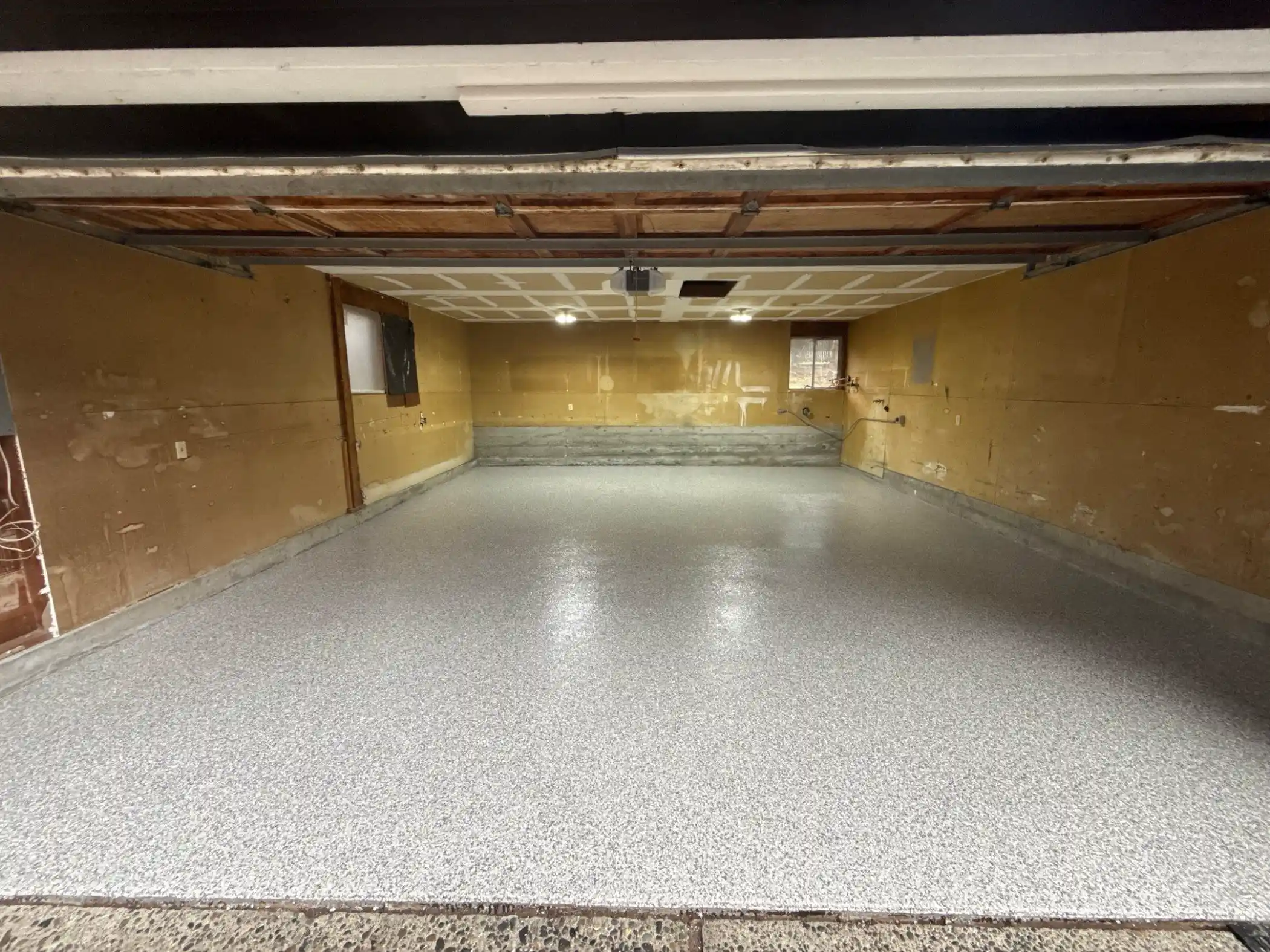 Slate Stone flake polyurea garage floor with plywood walls in a Kirkland home