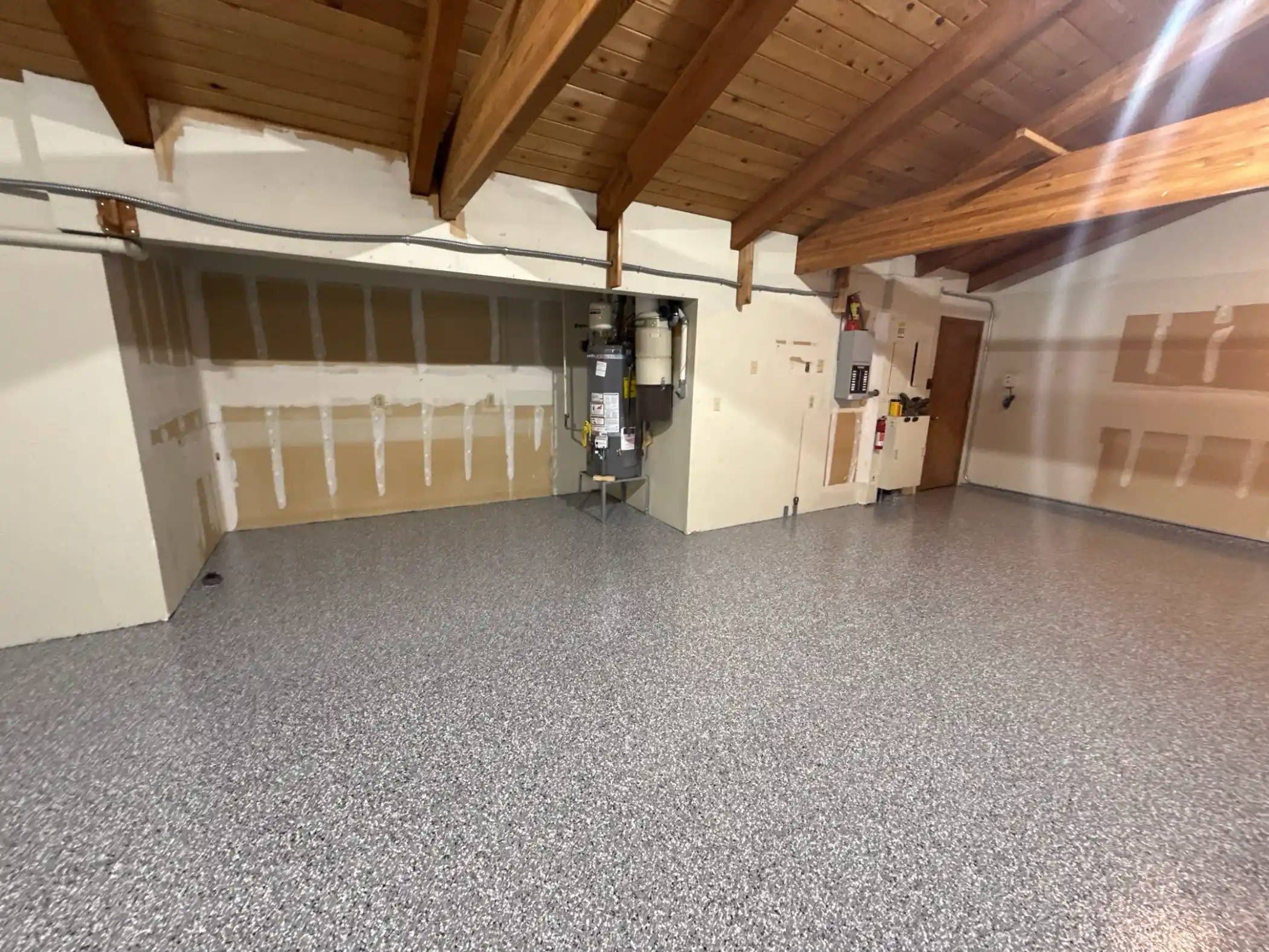 Wide view of an Edmonds garage with wood beam ceiling and a new Smoke flake floor
