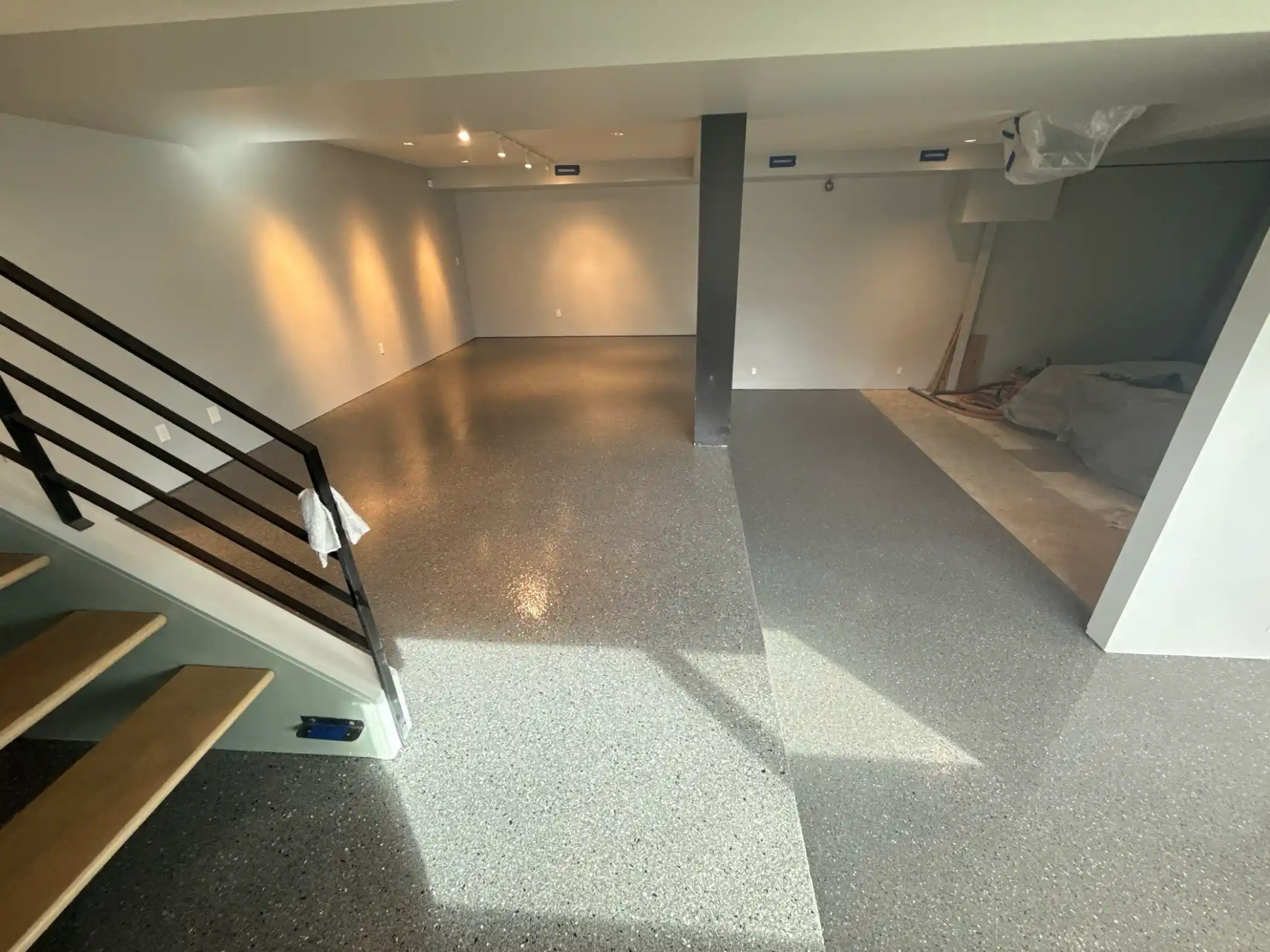 Slate flake polyurea basement floor with open-tread stairs in a modern Seattle home