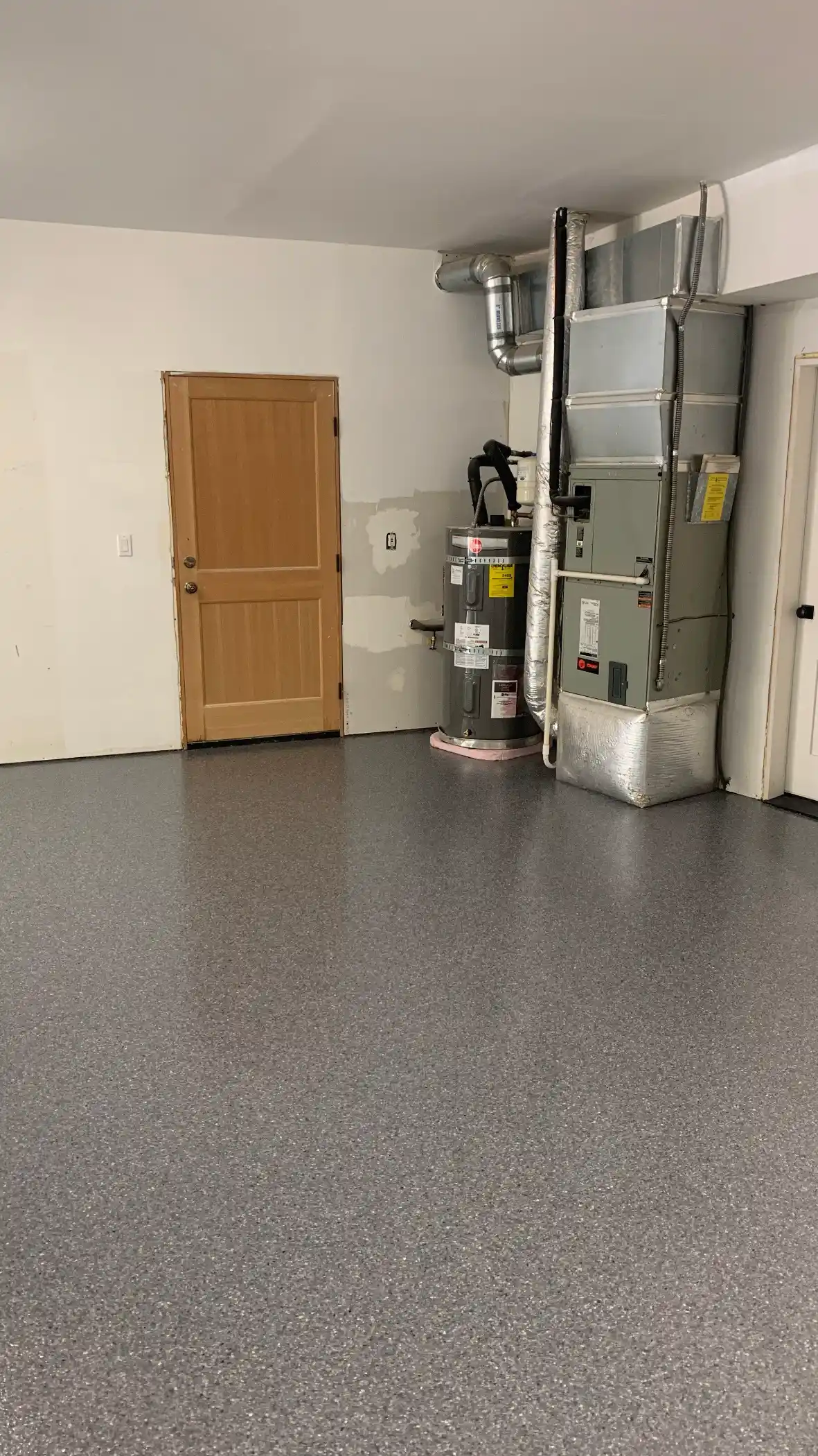 Back wall of a Belfair garage with wood door and grey flake floor