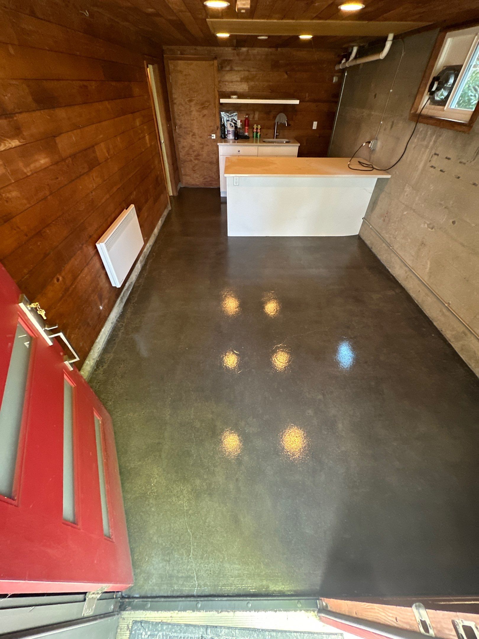 Glossy clear-coated concrete floor in a Seattle garage workroom with cedar walls and island