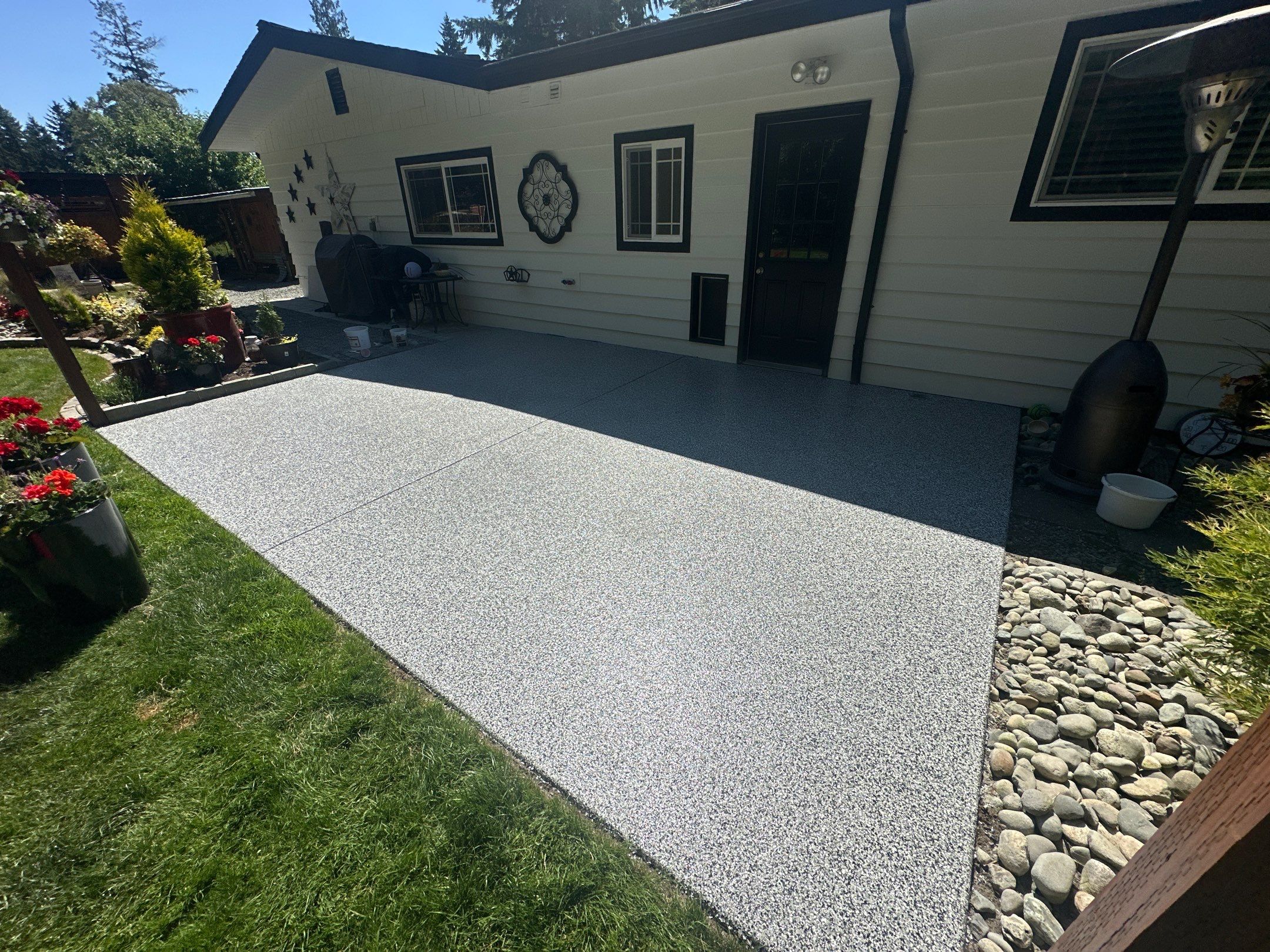 Domino flake polyurea front patio along a white single-story home in Woodinville