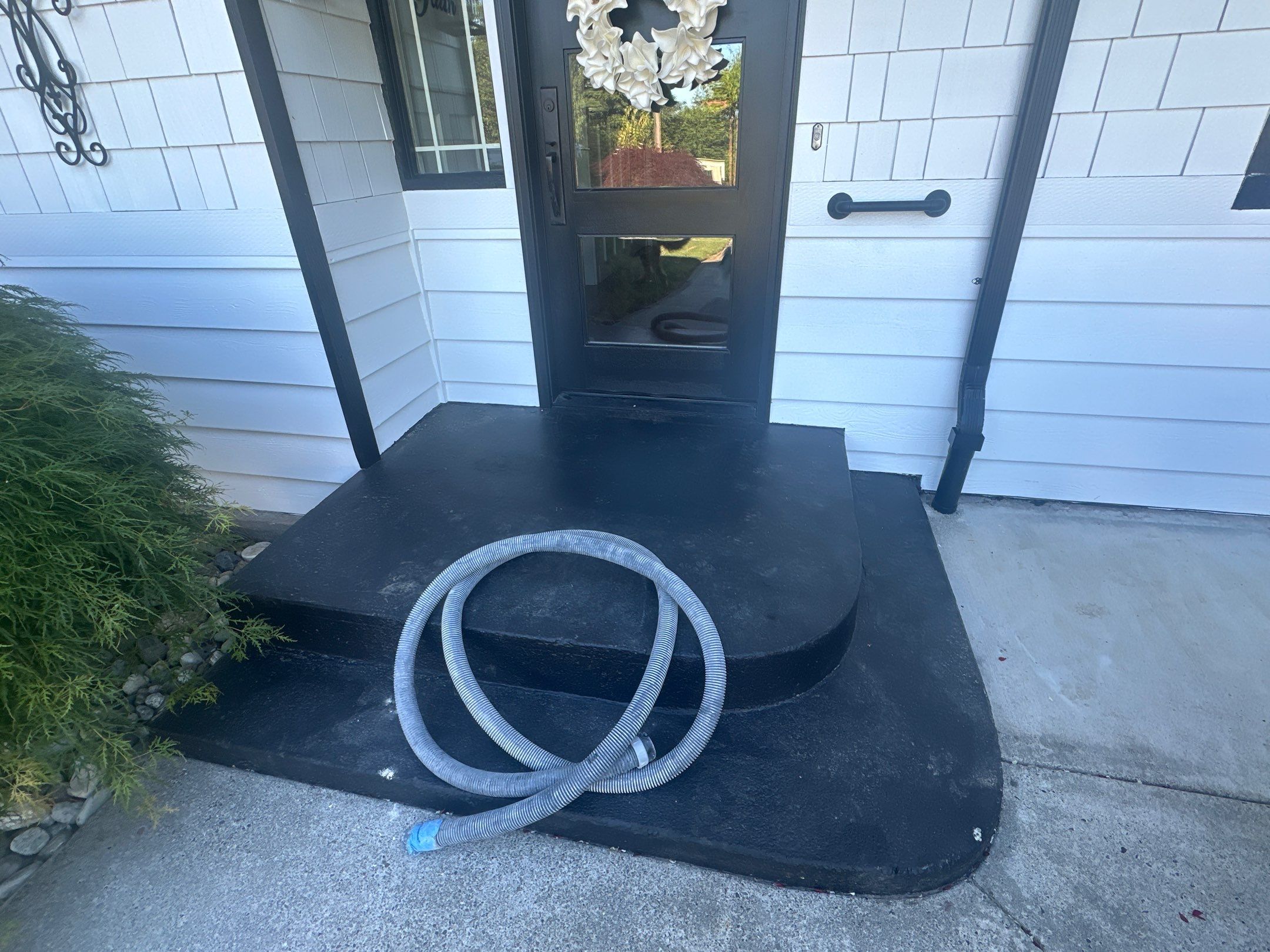 Rounded front entry steps with worn black paint before coating in Woodinville