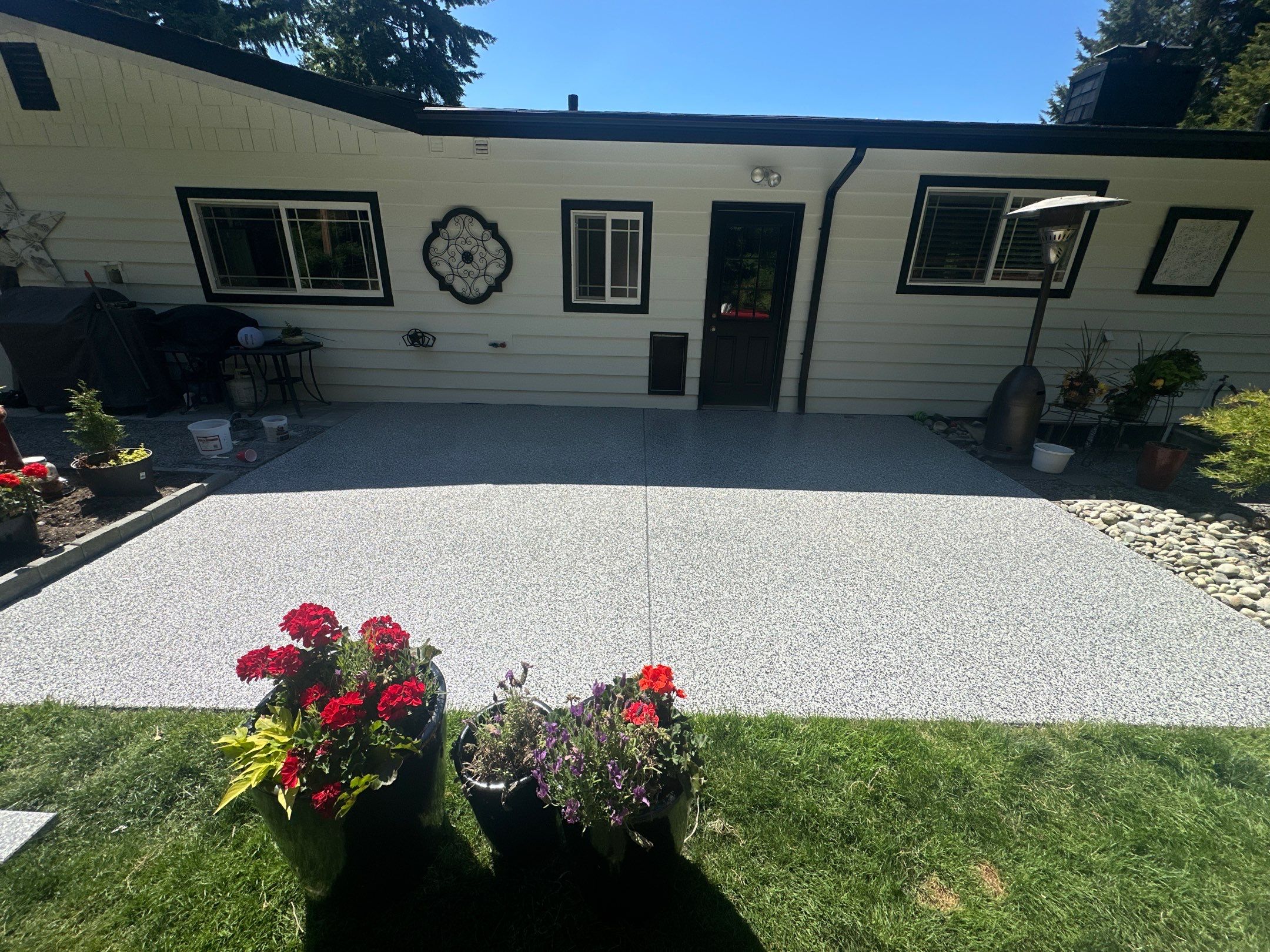Woodinville front patio in Domino polyurea flake with red flower pots