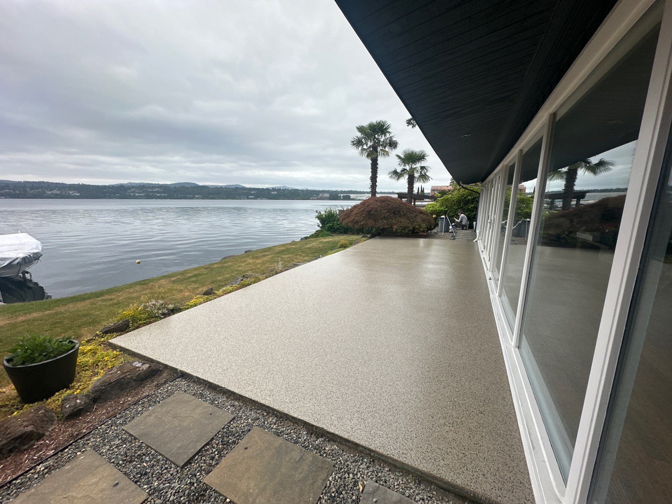 Pebble Beach flake polyurea patio along a glass wall above Lake Washington in Seattle