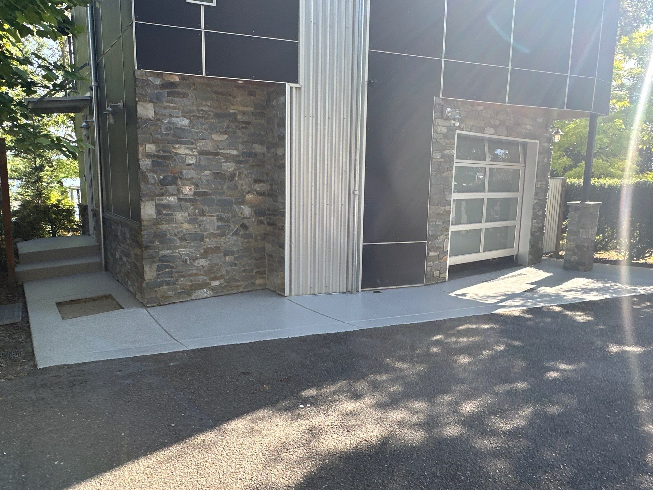 Blue Granite flake coated entry walk in front of a stone-clad modern home in Sammamish