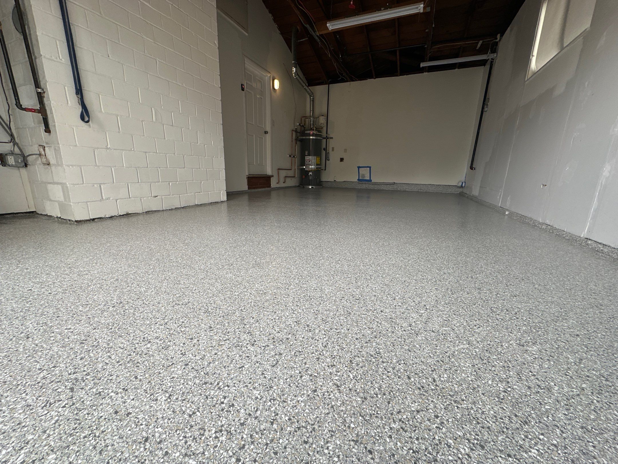 Mount Everest flake polyurea floor in a long single-bay Edmonds garage with block walls
