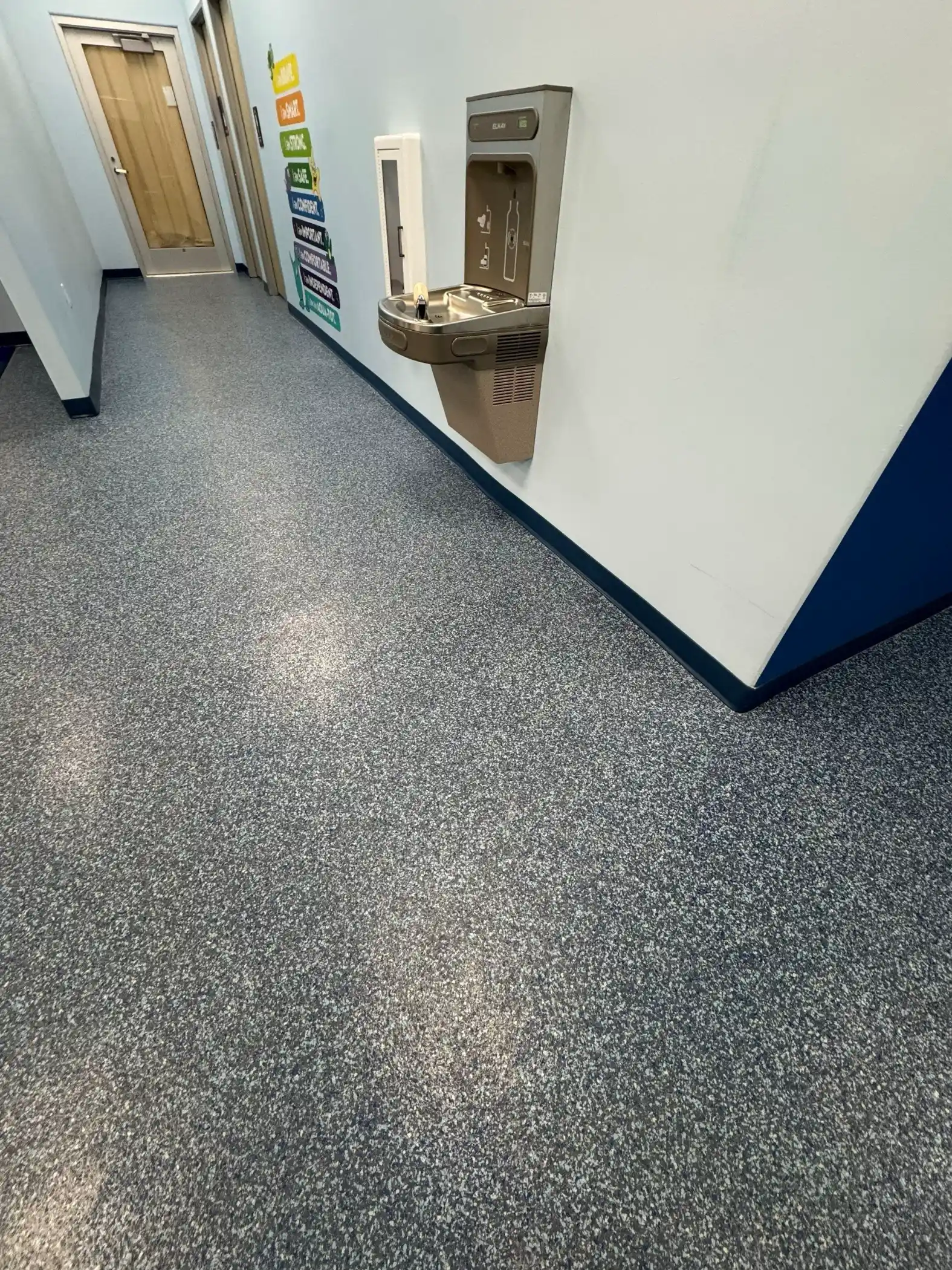 Hallway with water fountain and blue flake coated floor in a Lynnwood swim school