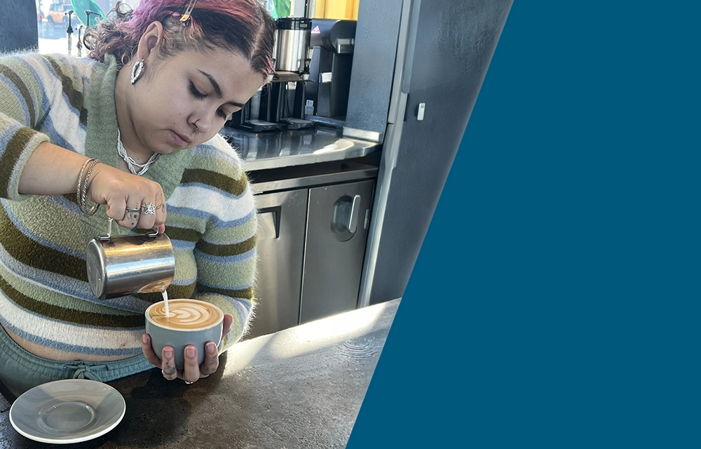 Apprentice barista pouring latte art during Pinnacol youth coffee apprenticeship program