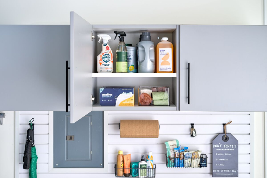 Garage cabinet interior with household cleaning products, paper towel holder, and wall-mounted organizers for everyday items.